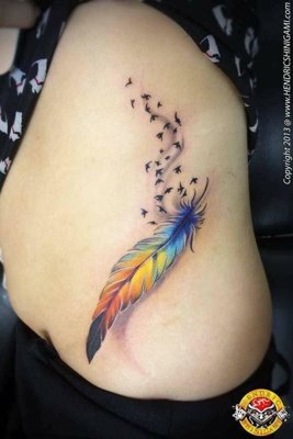 Tatouage plume colorée avec des petits oiseaux sur la hanche